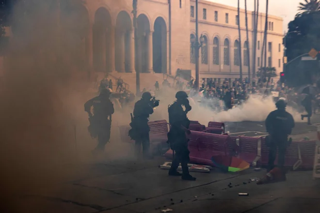 Policisti v Los Angelesu so se v oblakih solzivca približali improvizirani barikadi, medtem ko so se ob mestni hiši spopadli z demonstranti med protestom. FOTO: Etienne Laurent/AFP