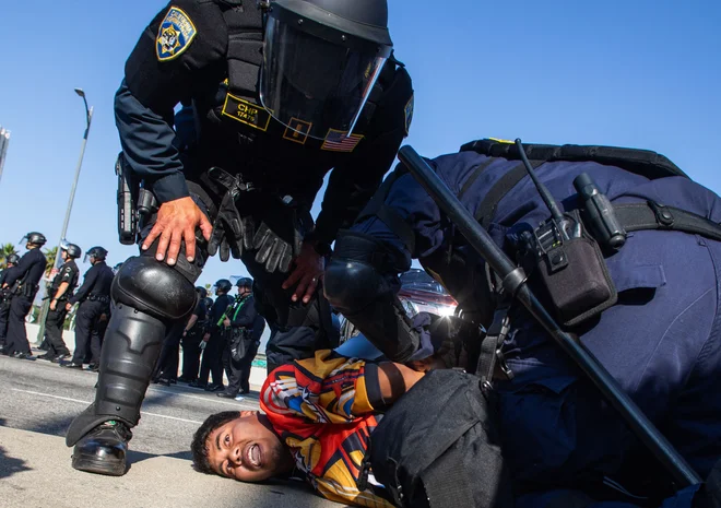 Policisti kalifornijske cestne patrulje aretirajo demonstranta na nadvozu avtoceste 101, ko se nadaljujejo protesti zaradi zveznih operacij proti priseljevanju v Los Angelesu. Trump je včeraj izjavil, da je Los Angeles napadel tuji sovražnik, in obljubil, da bo mesto osvobodil po večdnevnih protestih, ki so jih sprožili napadi na priseljence. Trump je v Los Angeles napotil 4000 vojakov, vključno s 700 ameriškimi marinci v aktivni službi, čeprav kalifornijske oblasti trdijo, da je ta poteza nepotrebna in da bo zaostrila razmere. Foto: Apu Gomes/Afp