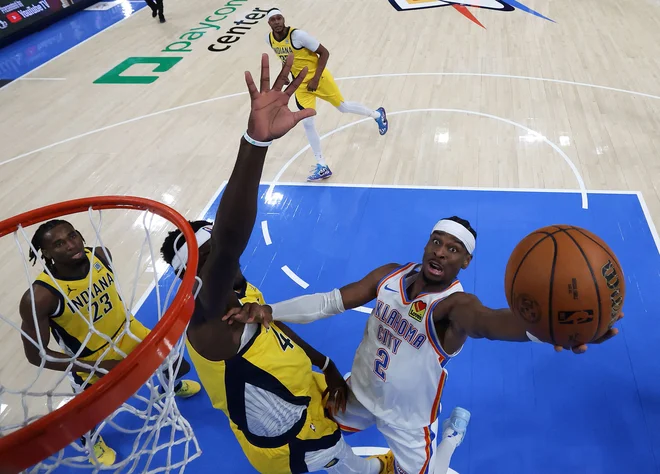Shai Gilgeous-Alexander je takole prodrl pod koš ob igralcu Indiane Pascalu Siakamu. FOTO: Matthew Stockman/AFP