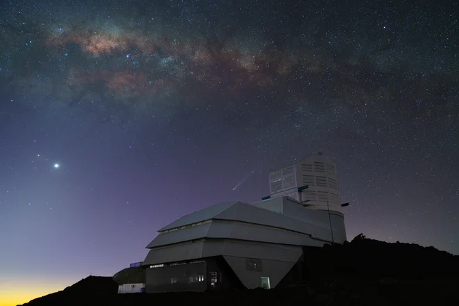Z observatorijem bodo v desetih letih slikali 40 milijard galaksij, zvezd in drugih nebesnih teles (svetla pika na levi je Venera, komet nad stavbo pa komet C/2023 A3 Tsuchinshan-Atlas).