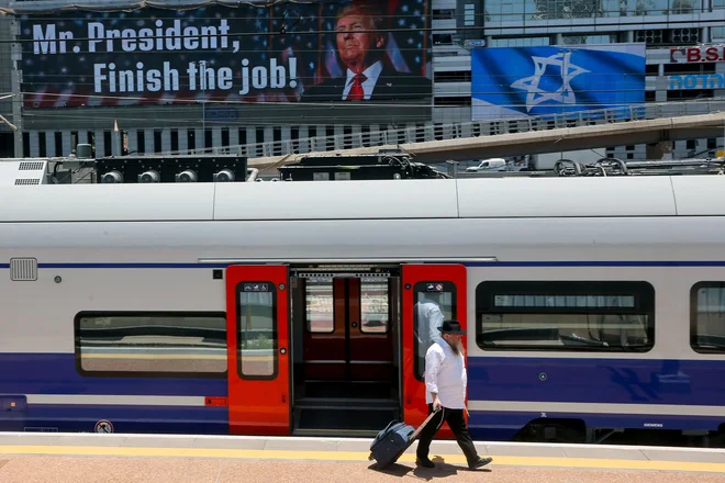 Ultraortodoksni Jud v Tel Avivu vleče kovček na železniški postaji pod oglasno desko s sporočilom ameriškemu predsedniku Donaldu Trumpu: »Gospod predsednik, dokončajte delo.« FOTO: Gil Cohen-magen/Afp