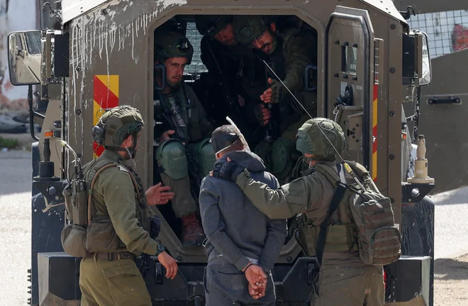 Izraelski vojaki s palestinskim ujetnikom. FOTO: Zain Jaafar/Afp