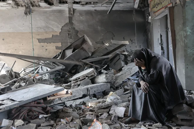 Palestinka joka med ruševinami šole Yaffa v soseski Tuffah v Gazi po nočnih izraelskih napadih. Izraelska vojska je v ponedeljek okrepila napade na severu Gaze. Med drugim poročajo o napadu na tri šolske stavbe v Zajtunu in Džabaliji, v katerih so nastanjeni razseljenci. Pri tem je bilo ubitih najmanj sedem ljudi. V zadnjih 24 urah je bilo v Gazi ubitih najmanj 72 ljudi, številni so po poročanju tamkajšnjih virov ujeti pod ruševinami. Foto: Omar Al-qattaa/Afp