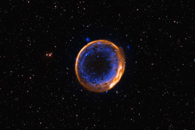 Ostanki supernove SNR 0509-67.5. FOTO: Eso/P. Das idr., zvezde v ozadju je posnel teleskop Hubble


 
