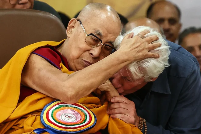 Ameriški igralec Richard Gere poljubi roko tibetanskemu duhovnemu voditelju dalajlami med molitveno slovesnostjo ob praznovanju njegovega 90. rojstnega dne v glavnem tibetanskem templju v McLeod Gandžu v bližini Dharamsale. Dalajlama je svojo 90-letnico včeraj obeležil z molitvijo za mir, saj Kitajska vztraja, da bo imela zadnjo besedo pri odločitvi, kdo bo nasledil tibetanskega duhovnega voditelja. Foto: Niharika Kulkarni/Afp