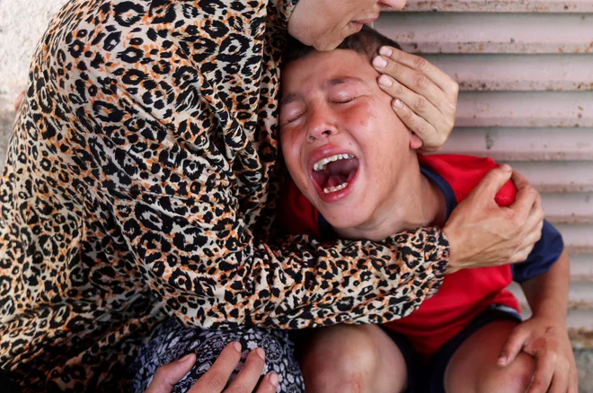 Palestinka tolaži sina, potem ko je v izraelskem napadu na bolnišnico izgubila hčerko. FOTO: Ramadan Abed/Reuters