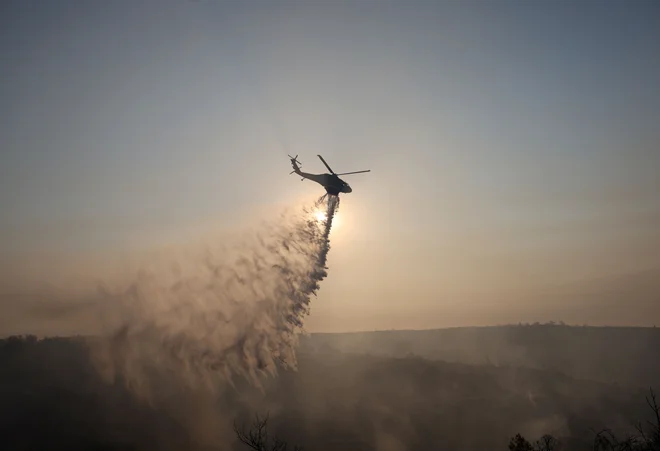 Gasilski helikopter pri gašenju gozdnega požara na Cipru. FOTO: Yiannis Kourtoglou/Reuters