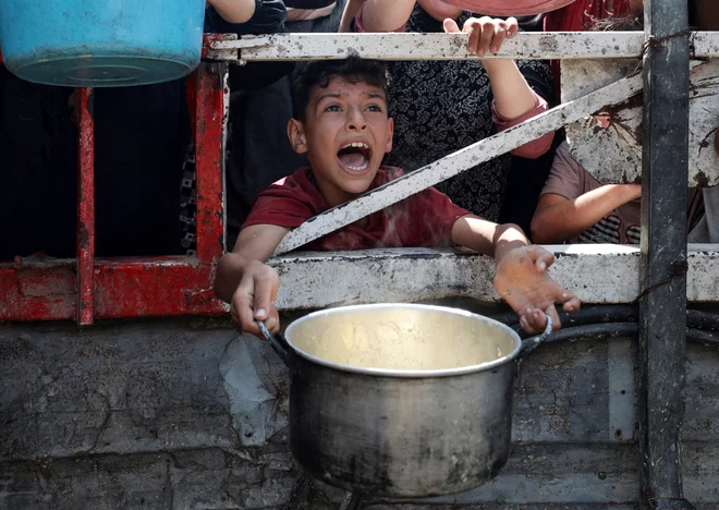 Palestinski deček čaka na hrano. FOTO: Khamis Al-rifi/Reuters