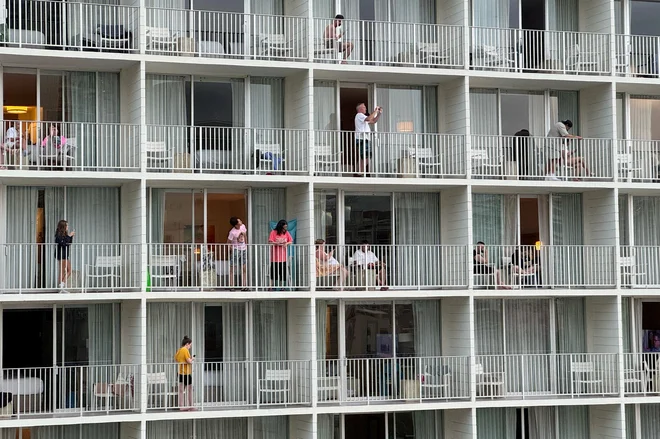 Turisti stojijo na balkonih letovišča Alohilani v Honoluluju na Havajih in gledajo proti plaži Waikiki, potem ko so oblasti opozorile na možnost cunamija po potresu. FOTO: Nichola Groom/Reuters