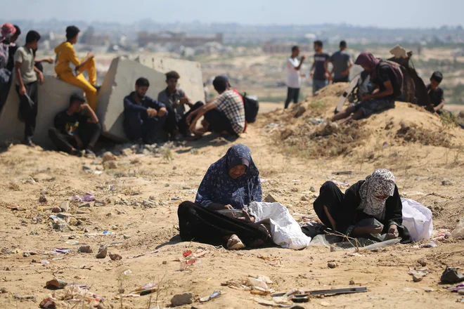 Palestinki iz osrednjega dela Gaze med prebiranjem peska, v katerem iščejo ostanke riža in stročnic. FOTO: Eyad Baba/AFP